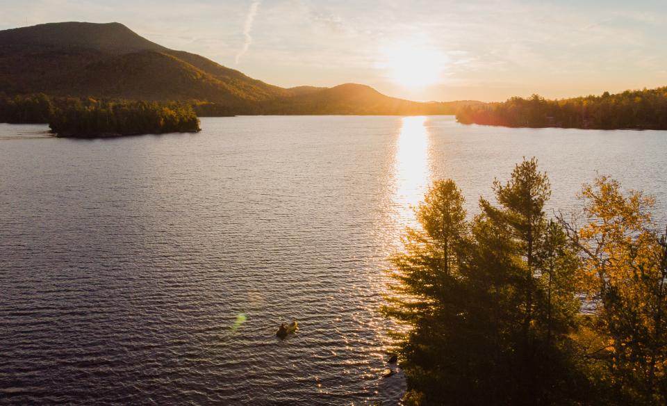 An aerial photo of a pack rafter in a lake during sunset.