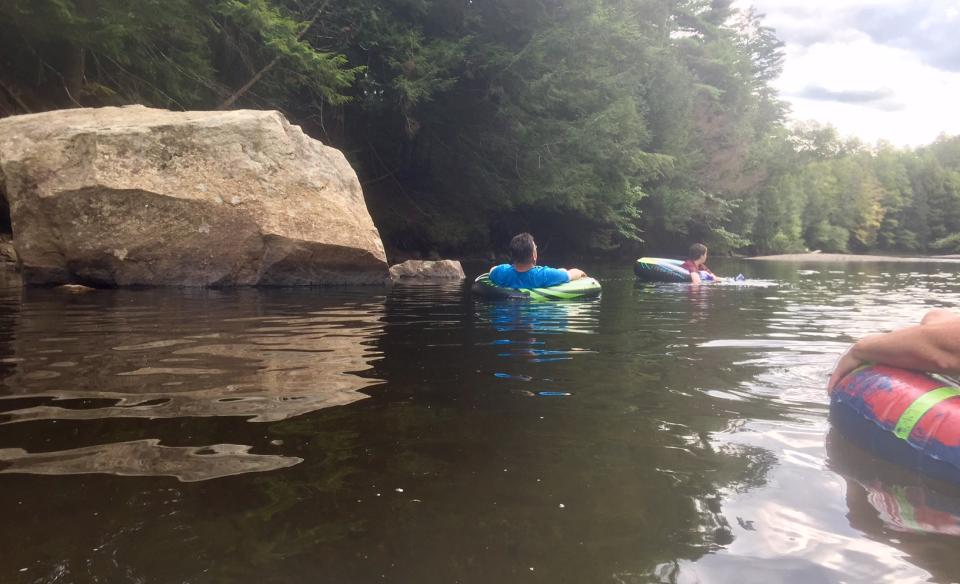 group of rafters floating by a big rock in the river