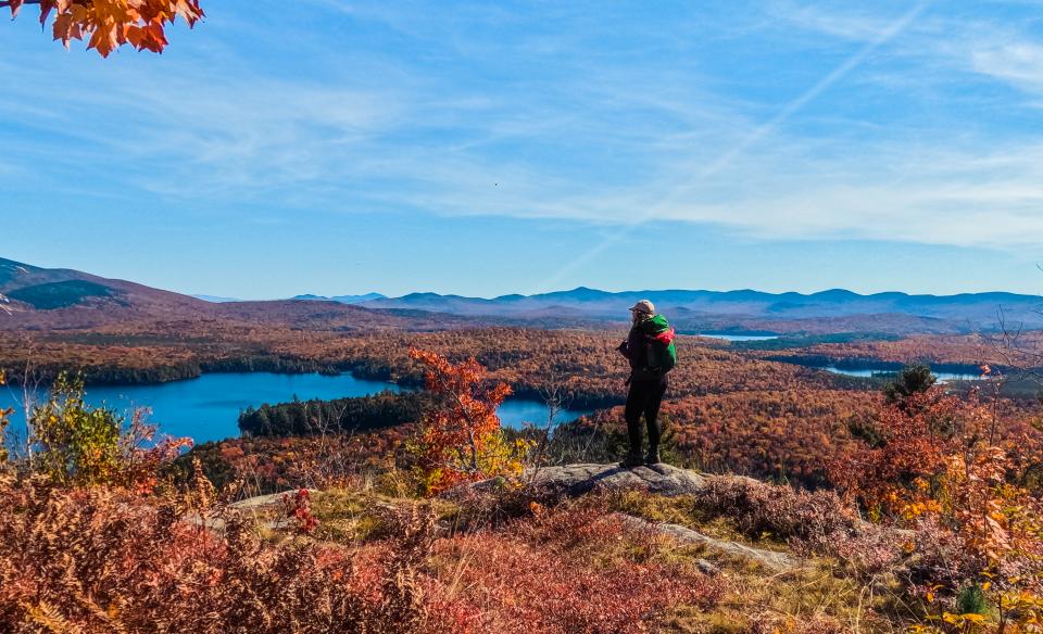 A hiker enjoys the fall scenery on Mud Pond Mountain.