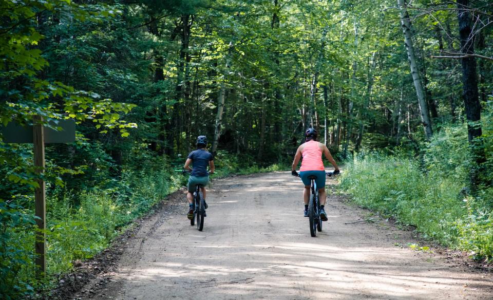 Two cyclists bike down a dirt road