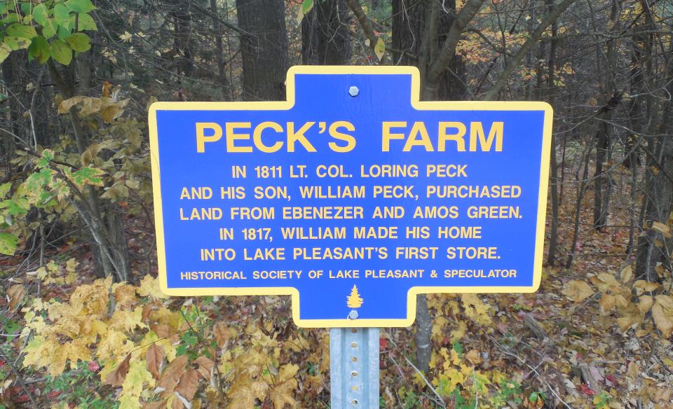 A blue historical sign for Peck's Farm