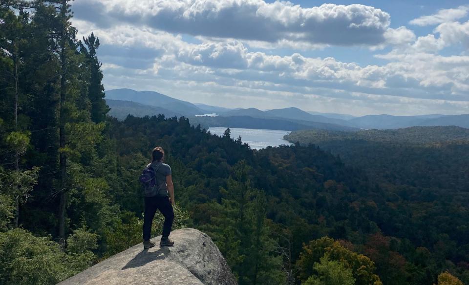 A hiker stands of a rock outcropping of Watch Hill.